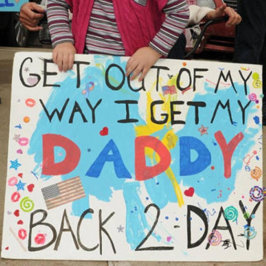 A child holding a funny and adorable airport greeting sign for her dad.