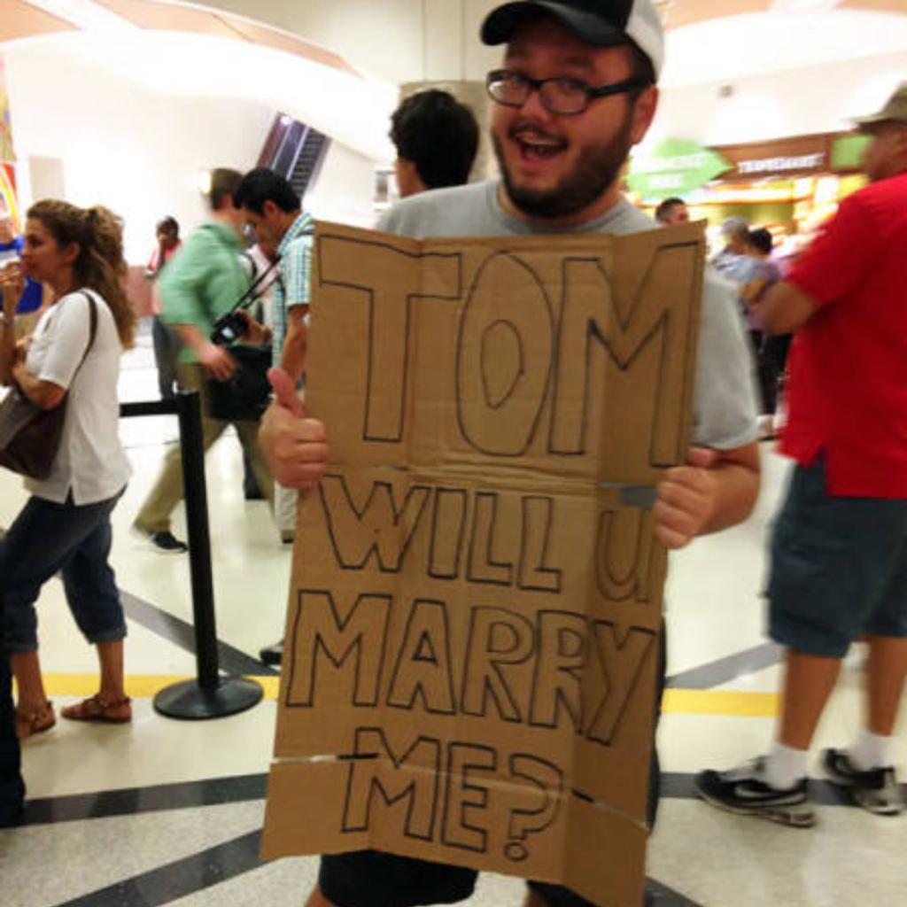 A man holding a funny airport greeting sign.