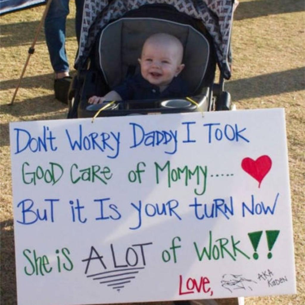 A baby with a funny airport greeting sign.