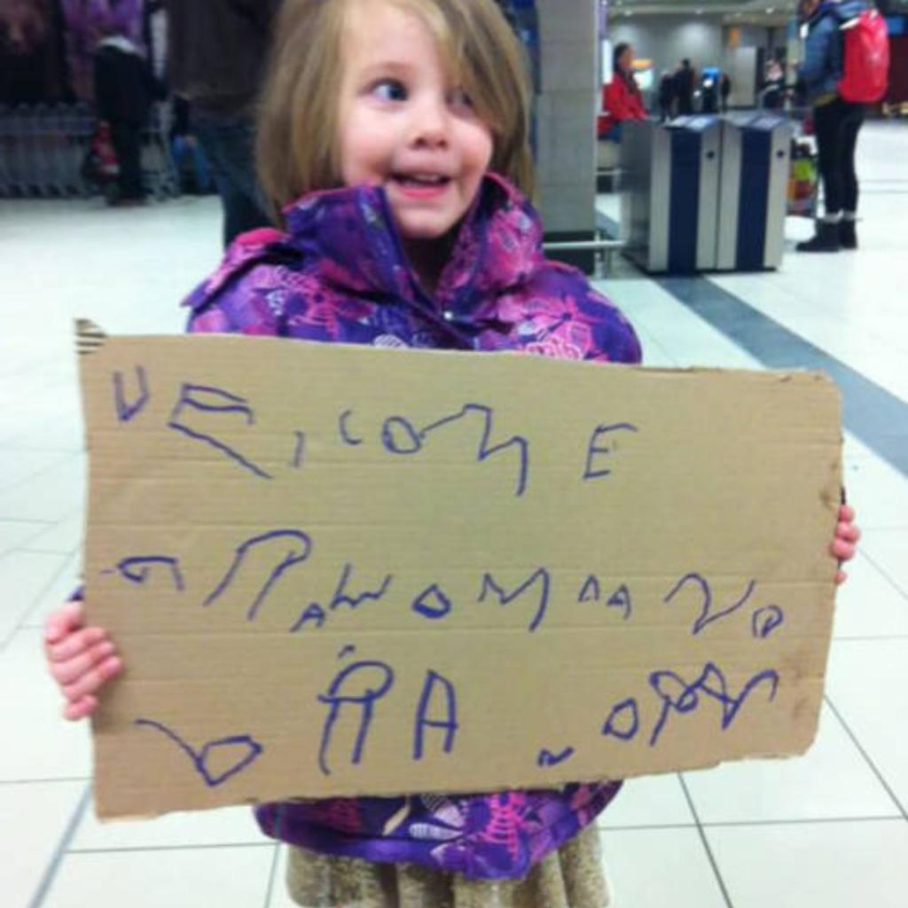 A child holding a funny, hand-written airport greeting sign.